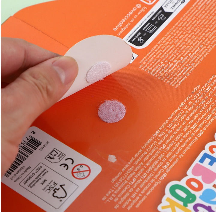 Hand applying a pink patch to an orange product with text and labels.