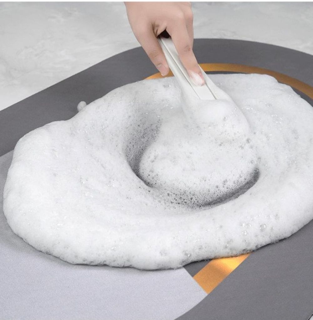 Hand using a tool to manipulate a large ball of white foam on a gray surface.