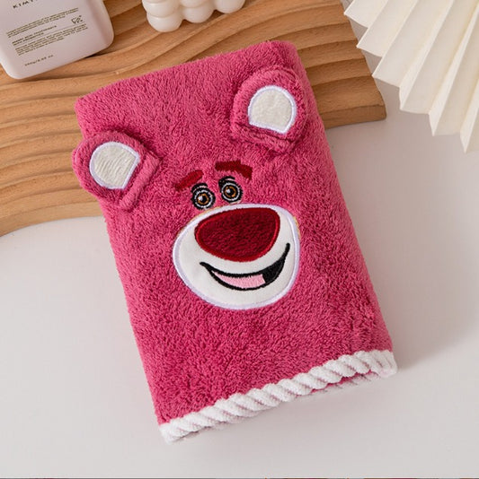 Pink towel with cartoon face design on a wooden surface