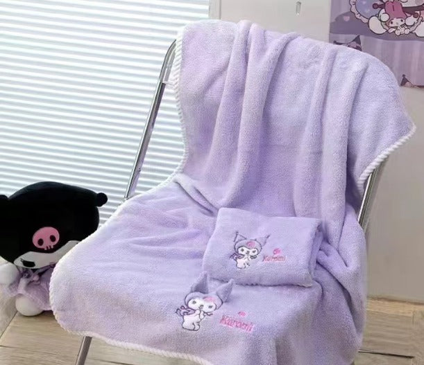 Purple towel with cartoon character and text draped over a chair, with a plush toy in the background.