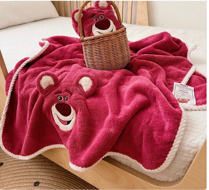 Red teddy bear-themed blanket draped over a surface with a wicker basket underneath.