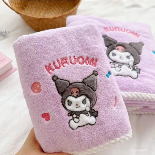 Pink towel with Kuruomi character design held by a hand, with another towel in the background.