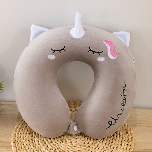 Unicorn-shaped neck pillow with a face on a woven mat